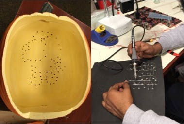 Pumpkin with holes along the outline of Beagle and LEDs being soldered together