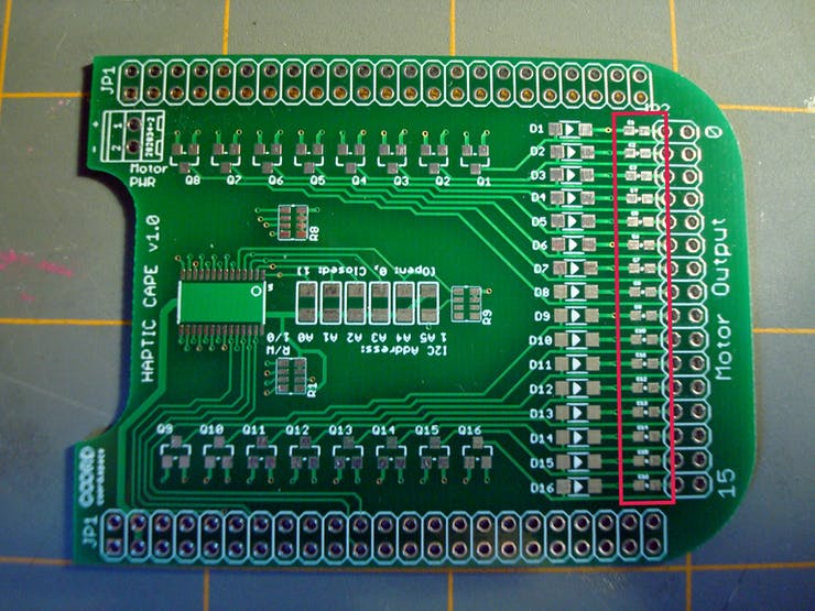 To start, identify the row of 0603 pads right next to the output header holes. These are for the CL10F104ZB8NNNC Capacitors. To follow the SparkFun SMD soldering guide, heat one row of these pads and drop a tiny bit of solder onto it, letting it flow out to cover the entire space. 