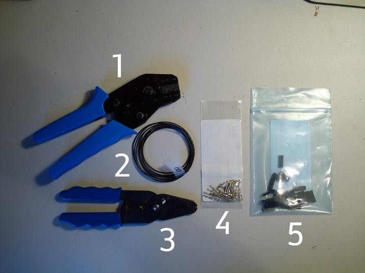 Counter-Clockwise from left. 1: Ratcheting hand crimper. 2: Our cut-wire lengths. 3: wire stripper. 4: The Molex SL female crimp terminals. 5: Molex SL 2 pin crimp housing.