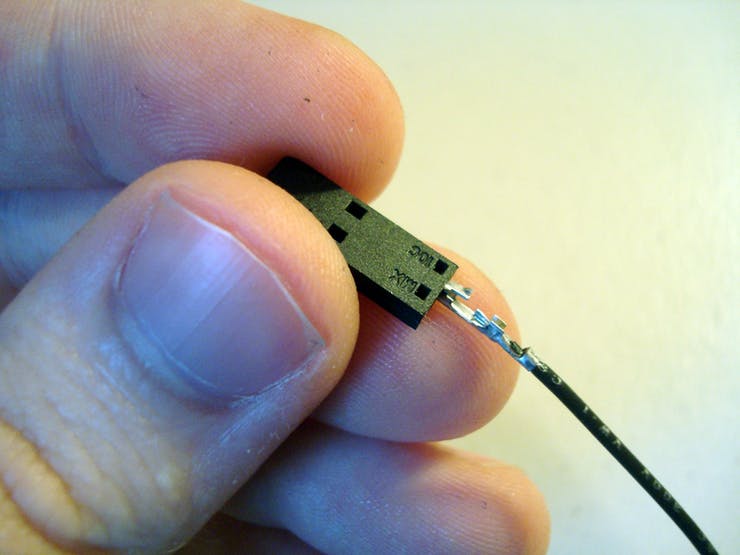 Aligning the metal lock on the crimp terminal with the hole on the connector, slowly push the terminal into the housing.